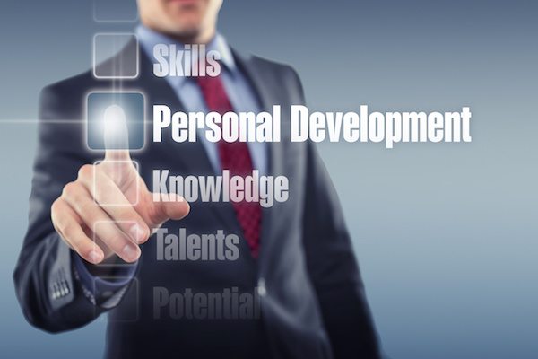 This image shows a person touching a button on a digital Holographic screen with the Text " Personal Development" on a digital interface. There are also different texts like " Skills, Knowledge, Talents, and Potential mentioned in other hexagonal buttons.